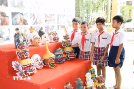 Các học sinh tham quan, tìm hiểu mão, mặt nạ của đồng bào Khmer. (Ảnh: Thanh Hòa/TTXVN)