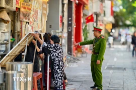 Lực lượng chức năng đi vận động hộ kinh doanh không lấn chiếm vỉa hè tại phố Phan Chu Trinh, phường Cửa Nam. (Ảnh: Quốc Lũy/TTXVN)