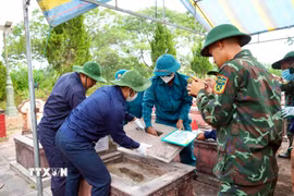 Các lực lượng tham gia khai quật, lấy mẫu AND phần mộ liệt sỹ. (Ảnh: Hữu Quyết/TTXVN)