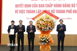 Đồng chí Đoàn Minh Huấn, Ủy viên Trung ương Đảng, Bí thư Tỉnh ủy Ninh Bình trao Quyết định và chúc mừng Đảng bộ thành phố Hoa Lư. (Ảnh: Đức Phương/TTXVN)