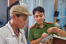 Cán bộ công an hướng dẫn người dân thao tác xin cấp phiếu lý lịch tư pháp trên ứng dụng VNeID. (Ảnh: Mai Trang/TTXVN)