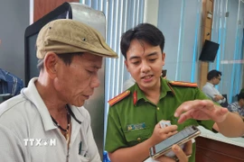 Cán bộ công an hướng dẫn người dân thao tác xin cấp phiếu lý lịch tư pháp trên ứng dụng VNeID. (Ảnh: Mai Trang/TTXVN)