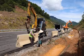 Công nhân hoàn thiện các hạng mục lan can, dải phân cách và biển báo trên tuyến cao tốc La Sơn-Hòa Liên. (Ảnh: Xuân Quý/TTXVN)