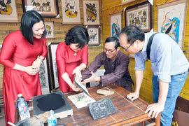 Du khách trải nghiệm in tranh dân gian Đông Hồ (Bắc Ninh). (Ảnh: Đồng Thúy/TTXVN)