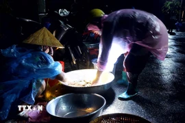 Ở "chợ ma" Tha La, mỗi người đều mang theo chiếc đèn pin để thuận lợi cho việc mua bán. (Ảnh: Công Mạo/TTXVN)