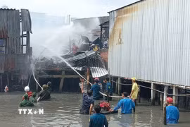 Các lực lượng phòng cháy, chữa cháy trên địa bàn huyện Năm Căn đã có mặt tại hiện trường hỗ trợ người dân chữa cháy, đồng thời không để xảy ra cháy lan. (Ảnh: TTXVN phát)
