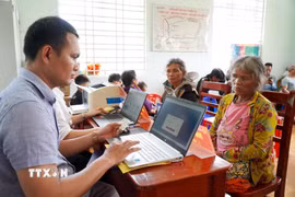 Người dân tộc Cor ở thôn Trà Thanh, xã Thanh Bồng (Quảng Ngãi) được thành viên Tổ công tác lưu động hỗ trợ thực hiện thủ tục hành chính. (Ảnh: Lê Phước Ngọc/TTXVN)