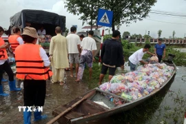 Các đoàn tình nguyện vận chuyển hàng hóa lên ghe để đưa vào những vùng ngập sâu ở thành phố Huế. (Ảnh: Đỗ Trưởng/TTXVN)