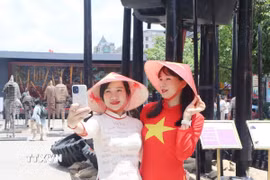Người dân diện áo dài truyền thống, cờ đỏ sao vàng ghi lại những khoảnh khắc đẹp trong dịp lễ kỷ niệm. (Ảnh: Thu Hương/TTXVN)