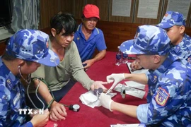 Cán bộ, chiến sỹ tàu cảnh sát biển 4035, Bộ Tư lệnh Vùng Cảnh sát biển 4 chăm sóc, hỗ trợ y tế cho nạn nhân gặp nạn trên biển. (Ảnh: TTXVN phát)
