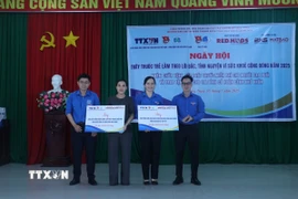 Đại diện Đoàn Thanh niên Trung tâm thông tin TTXVN khu vực phía Nam, Đoàn thanh niên Bệnh viện Ung bướu Thành phố Hồ Chí Minh trao bảng quà tượng trưng cho chính quyền địa phương. (Ảnh: Bùi Giang/ TTXVN)