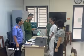 Kiểm sát viên Viện Kiểm sát Nhân dân tỉnh Thanh Hóa kiểm sát việc tống đạt Quyết định khởi tố và Lệnh tạm giam đối với bị can Trịnh Thị Vân Anh và Nguyễn Thị Thanh Ngần. (Ảnh: TTXVN phát)