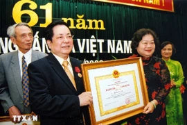 Phó Chủ tịch nước Trương Mỹ Hoa trao Huân chương Lao động hạng Nhì tặng Phó Tổng Giám đốc Thông tấn xã Việt Nam Trương Đức Anh nhân dịp kỷ niệm 61 năm Ngày truyền thống Thông tấn xã Việt Nam, tháng 9/2006. (Ảnh: TTXVN)