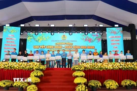 Ông Nguyễn Đình Khang, Chủ tịch Tổng Liên đoàn Lao động Việt Nam và ông Nguyễn Phước Lộc, Phó Bí thư Thành ủy Thành phố Hồ Chí Minh trao tặng vé máy bay cho công nhân lao động về quê đón Tết. (Ảnh: Thanh Vũ/TTXVN)