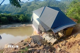 Sạt lở đường Quốc lộ 217, đoạn qua xã Trung Hạ, tỉnh Thanh Hóa làm một ngôi nhà sắp sụp xuống sông. (Ảnh: Nguyễn Nam/TTXVN)