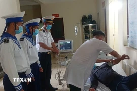 Bác sỹ Bệnh xá đảo Trường Sa kiểm tra sức khỏe bệnh nhân Lê Văn Đông. (Ảnh: TTXVN phát)