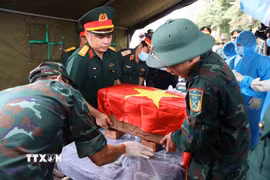 Trang trọng thực hiện quy trình khai quật, đưa hài cốt liệt sĩ chưa xác định danh tính về khu vực lấy mẫu sinh phẩm liệt sỹ tại Nghĩa trang Liệt sỹ Ngọc Hồi (xã Thanh Trì). (Ảnh: Văn Điệp/TTXVN)