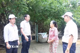 Lãnh đạo Ủy ban Nhân dân xã Điện Bàn Tây vận động người dân nhận tiền đền bù giải phóng mặt bằng phục vụ các công trình trọng điểm. (Ảnh: Hữu Ka/TTXVN phát)