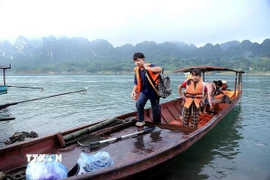 Các em học sinh xuống thuyền vào bờ cập bến cảng Ngòi Hoa. (Ảnh: Thanh Hải/TTXVN)