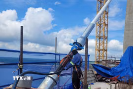 Công nhân căng bó cáp dây văng đầu tiên tại cầu Phước An. (Ảnh: Hoàng Nhị/TTXVN)