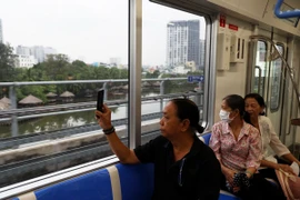 Người dân lưu lại hình ảnh đô thị bên ngoài khi trải nghiệm tuyến metro số 1. (Ảnh: Huyền Trinh/TTXVN)