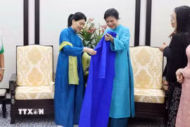 Bà Ngô Phương Ly, Phu nhân Tổng Bí thư Tô Lâm giới thiệu và tặng áo dài truyền thống Việt Nam cho bà Loo Tze Lui, Phu nhân Thủ tướng Singapore Lawrence Wong. (Ảnh: Phạm Kiên/TTXVN)
