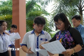 Giám thị tại điểm thi Trường THPT Hòn Đất (Kiên Giang) kiểm tra thông tin thí sinh trước khi vào phòng thi. (Ảnh: Văn Sĩ/TTXVN)