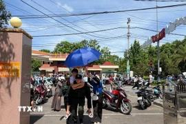 Cán bộ chiến sỹ Trung đoàn cảnh sát cơ động hỗ trợ cõng học sinh bị gãy chân đi thi. (Ảnh: Sỹ Thắng/TTXVN)