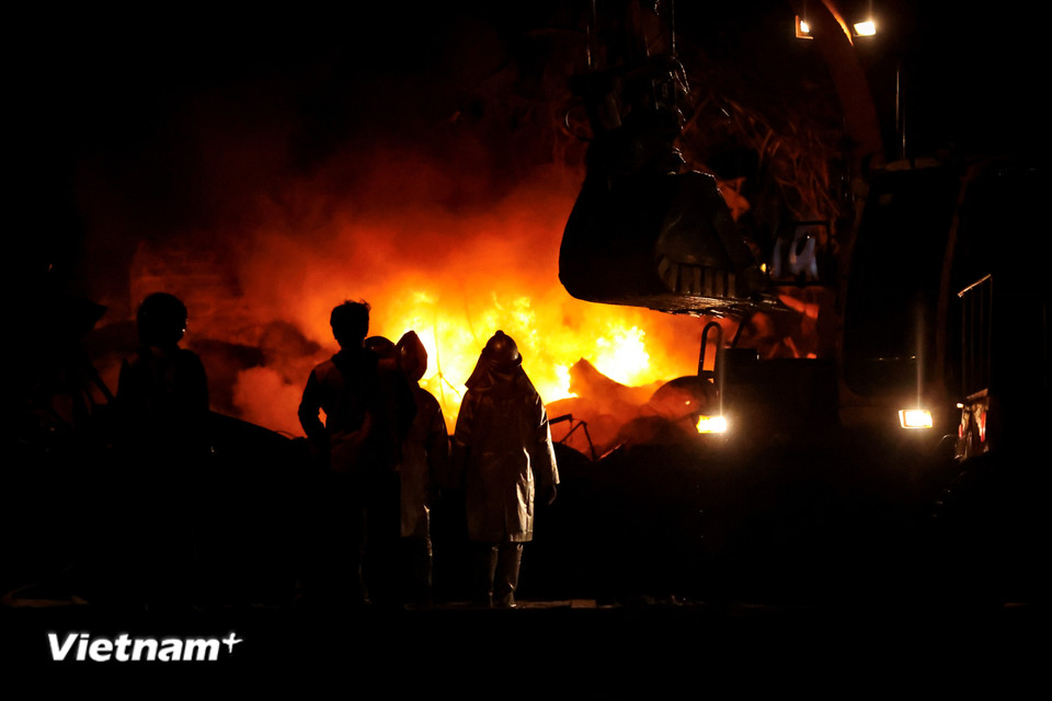 Ngọn lửa bùng lên dữ dội, lực lượng chức năng phải dùng máy xúc để mở đường chữa cháy. (Ảnh: Hoài Nam/Vietnam+)