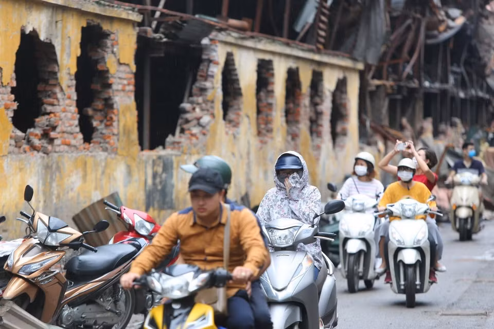 Người dân sinh sống tại đây phải đeo khẩu trang mỗi khi đi qua khu vực cháy nhà máy Bóng đèn Phích nước Rạng Đông. (Ảnh: Thành Đạt/TTXVN)