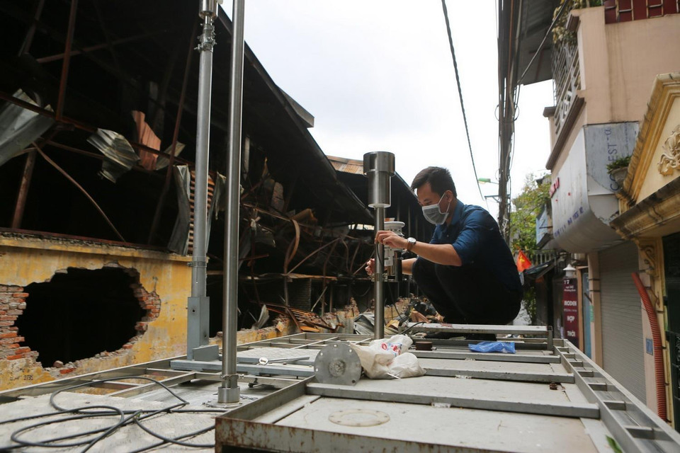 Đoàn cán bộ Chi cục Bảo vệ môi trường và Trung tâm quan trắc môi trường Hà Nội lắp đặt máy đo không khí và độ nhiễm độc tại hiện trường. (Ảnh: Thành Đạt/TTXVN)