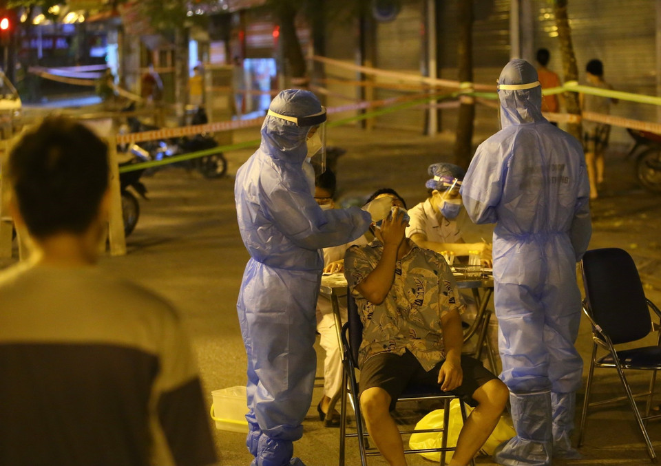  Lực lượng y tế lấy mẫu xét nghiệm đối với những người có liên quan đến ca nghi nhiễm COVID-19 tại số 307 phố Trần Đại Nghĩa. (Ảnh: Hoàng Hiếu/TTXVN)