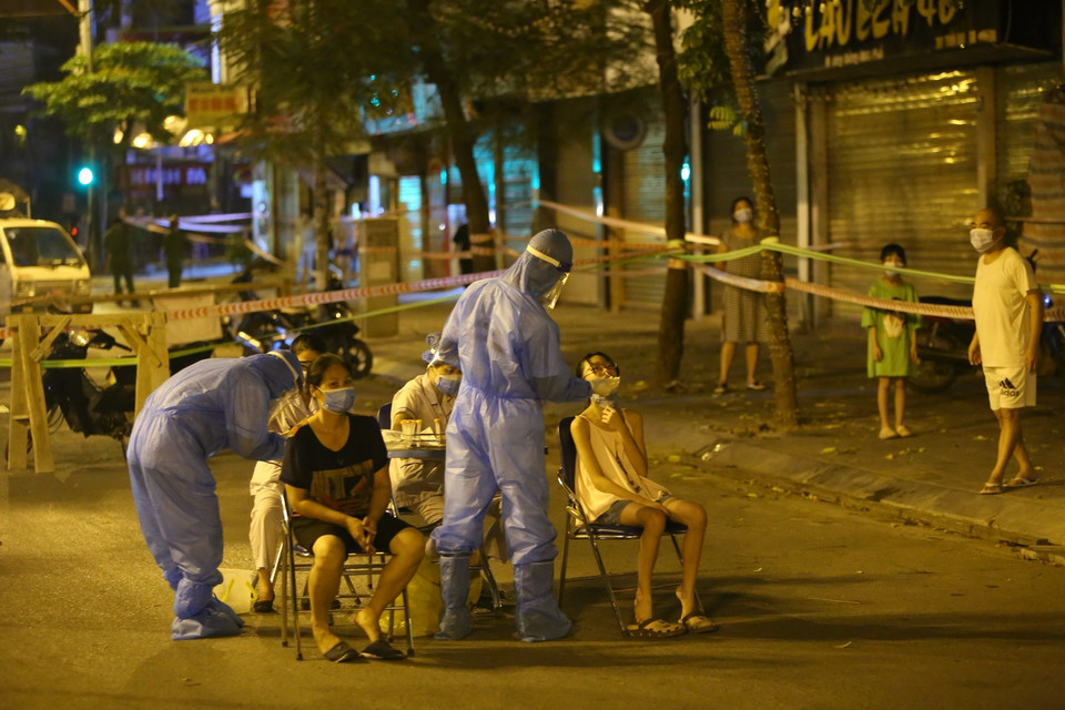 Lực lượng y tế lấy mẫu xét nghiệm đối với những người có liên quan đến ca nghi nhiễm COVID-19 tại số 307 phố Trần Đại Nghĩa. (Ảnh: Hoàng Hiếu/TTXVN)