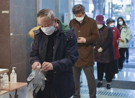 Cử tri xếp hàng chờ bỏ phiếu tại điểm bầu cử Quốc hội khóa 21 ở Seoul, Hàn Quốc. Để đảm bảo an toàn cho cử tri, NEC yêu cầu tất cả những người có mặt tại các điểm bỏ phiếu đều phải đeo khẩu trang, găng tay, giữ khoảng cách tối thiếu 1m và được kiểm tra thân nhiệt trước khi vào bỏ phiếu. (Ảnh: Kyodo/TTXVN)