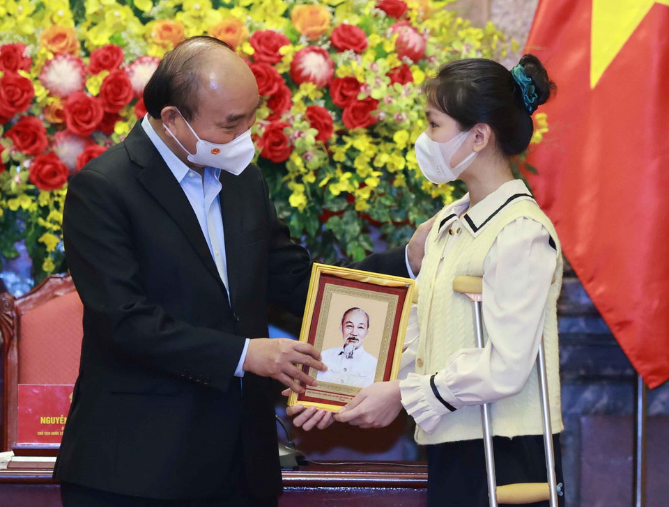 Chủ tịch nước Nguyễn Xuân Phúc tặng chân dung Chủ tịch Hồ Chí Minh cho học sinh xuất sắc trong cuộc thi “Vì một Việt Nam tất thắng.” (Ảnh: Thống Nhất/TTXVN)