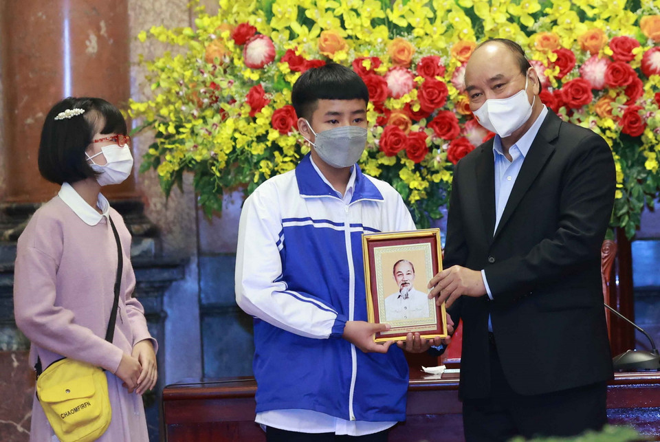Chủ tịch nước Nguyễn Xuân Phúc tặng chân dung Chủ tịch Hồ Chí Minh cho các học sinh. (Ảnh: Thống Nhất/TTXVN)