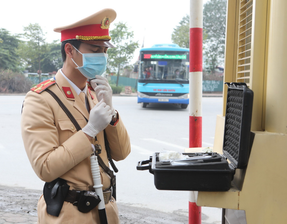 Cảnh sát giao thông Hà Nội kiểm tra trang thiết bị sử dụng phương tiện an toàn kiểm tra nồng độ cồn trong khí, đeo khẩu trang y tế trước khi làm nhiệm vụ. (Ảnh: Doãn Tấn/TTXVN)