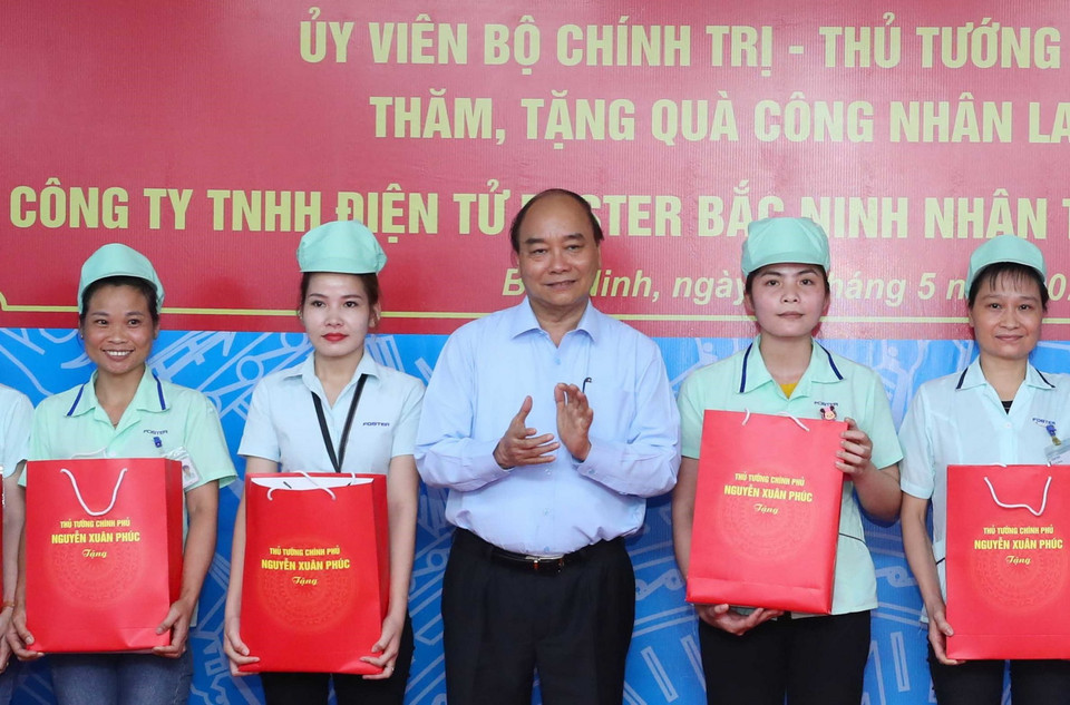 Thủ tướng Nguyễn Xuân Phúc tặng quà cho công nhân Công ty TNHH Điện tử Foster (Việt Nam). (Ảnh: Thống Nhất/TTXVN)