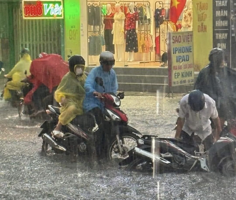 Người dân vất vả di chuyển giữa dòng nước ngập trên đường Nguyễn Ảnh Thủ, huyện Hóc Môn. (Ảnh: TTXVN phát)