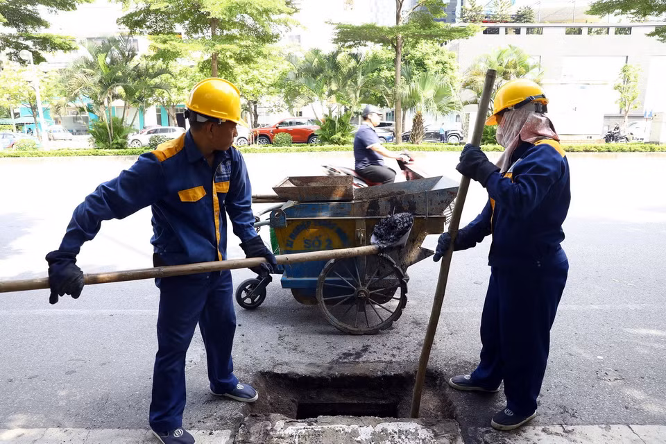 Công nhân Xí nghiệp Thoát nước số 2 nạo vét cống trên phố Dương Đình Nghệ, quận Cầu Giấy. (Ảnh: Huy Hùng/TTXVN)