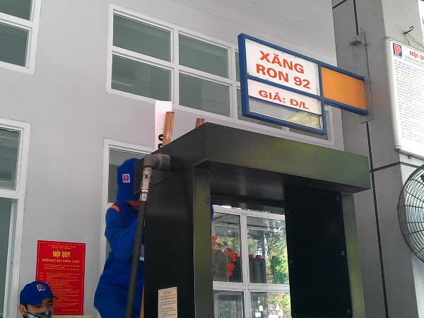 Nhân viên cây xăng ngã 5 Trần Hưng Đạo, Hoàn Kiếm (Hà Nội) "thoăn thoắt" gỡ biển giá cũ lúc 14 giờ 5 phút. (Ảnh: PV/Vietnam+)