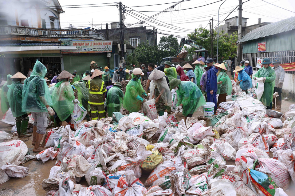 Bộ đội và người dân thôn Liệp Mai, xã Ngọc Liệp, huyện Quốc Oai khẩn trương chuẩn bị các bao tải chứa đất để gia cố đoạn đê bao sông Tích. (Ảnh: Vũ Sinh/TTXVN)