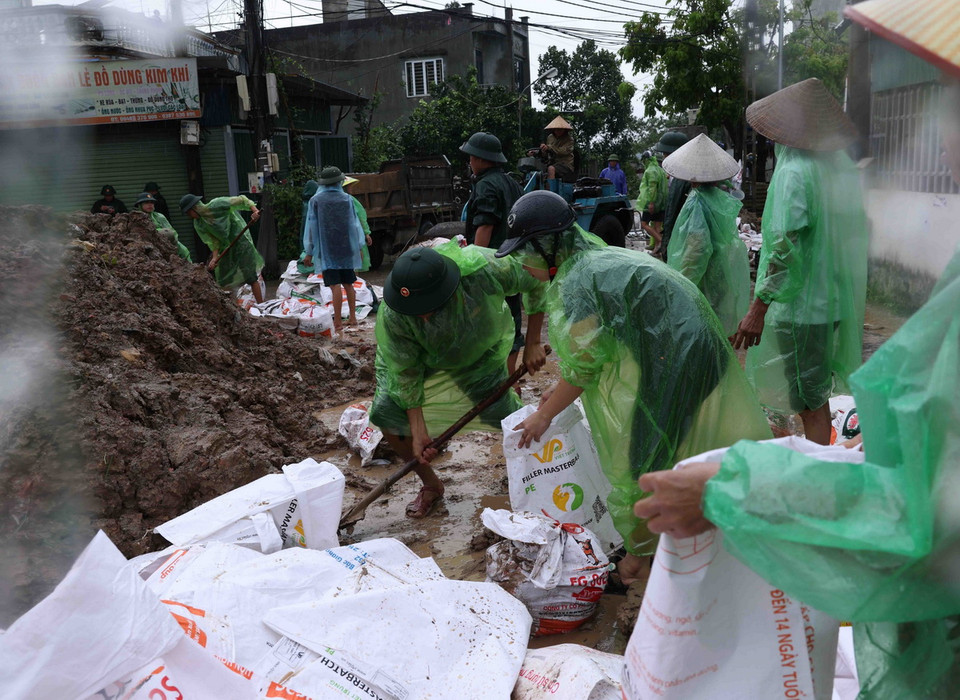 Bộ đội và người dân thôn Liệp Mai, xã Ngọc Liệp, huyện Quốc Oai khẩn trương chuẩn bị các bao tải chứa đất để gia cố đoạn đê bao sông Tích. (Ảnh: Vũ Sinh/TTXVN)