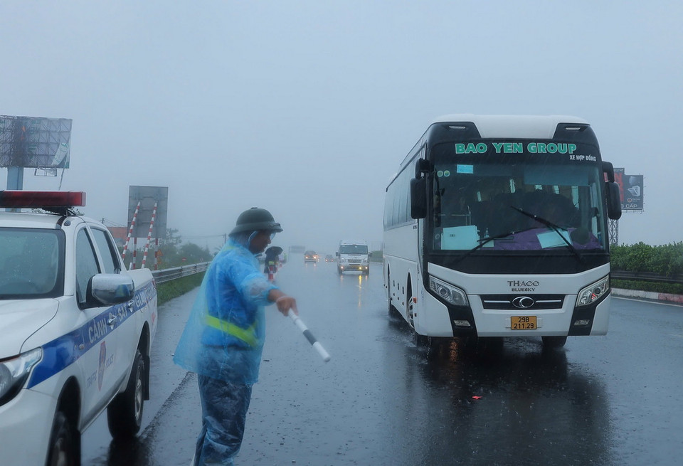 Nhân viên Công ty BOT Pháp Vân-Cầu Giẽ hướng dẫn các phương tiện đi sang bên trái, tránh vùng ngập sâu bên phải tại đoạn Km191+500 trên cao tốc Pháp Vân-Cầu Giẽ (ảnh chụp lúc 10h25 ngày 11/9). (Ảnh: Hoàng Hiếu/TTXVN)