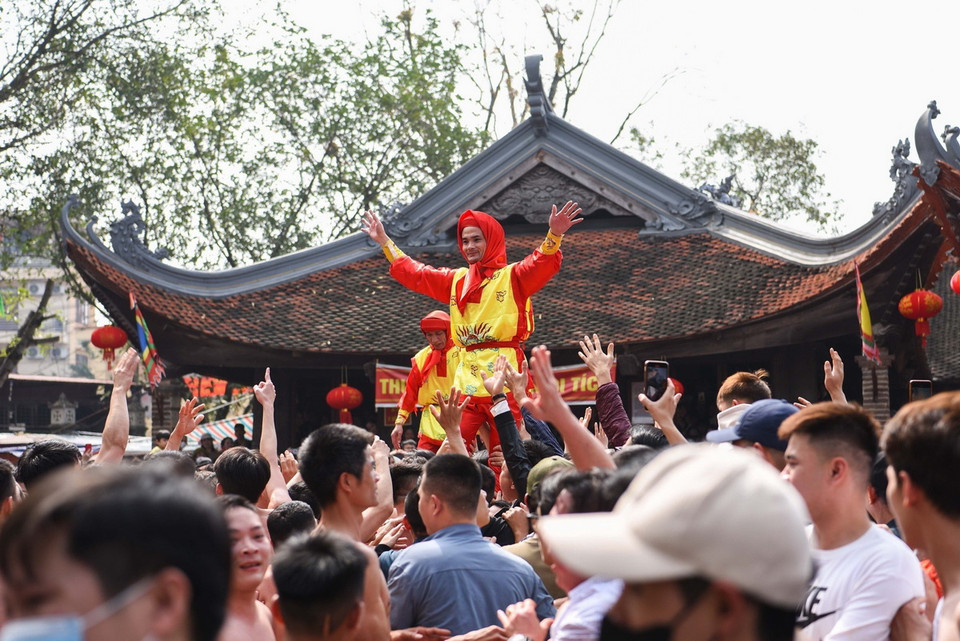 Quan đám được công trên vai bởi những chàng trai đang độ sung sức làm động tác múa như muốn cổ động tinh thần quân lính. (Ảnh: Đỗ Huyền/TTXVN)