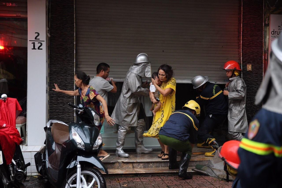 Lực lượng chữa cháy đưa người dân ra khỏi hiện trường. (Ảnh: Dương Giang/TTXVN)