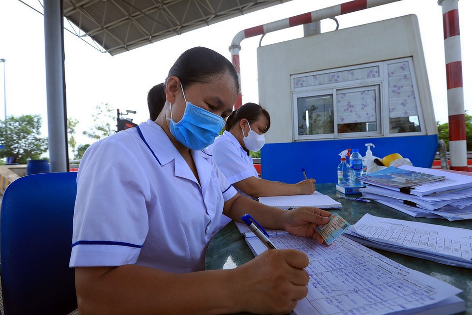  Nhân viên y tế huyện Ba Vì lấy thông tin khai báo y tế và cá nhân của người dân tại chốt kiểm dịch đầu cầu Văn Lang. (Ảnh: Tuấn Anh/TTXVN)