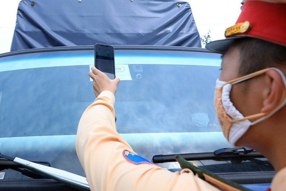  Lực lượng cảnh sát giao thông đội 6 quét mã QR các phương tiện vận tải ra, vào thành phố. (Ảnh: Tuấn Anh/TTXVN)