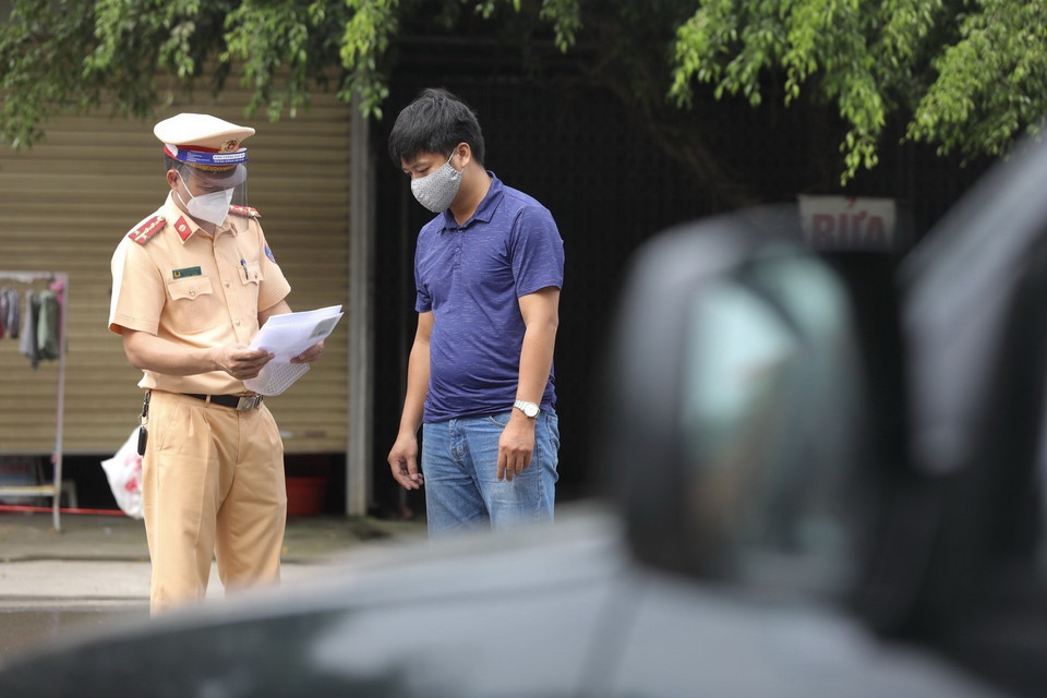  Lực lượng chức năng tại chốt kiểm soát đầu cầu Trung Hà (huyện Ba Vì) kiểm tra giấy tờ của người và phương tiện khi qua chốt. (Ảnh: Minh Quyết/TTXVN)