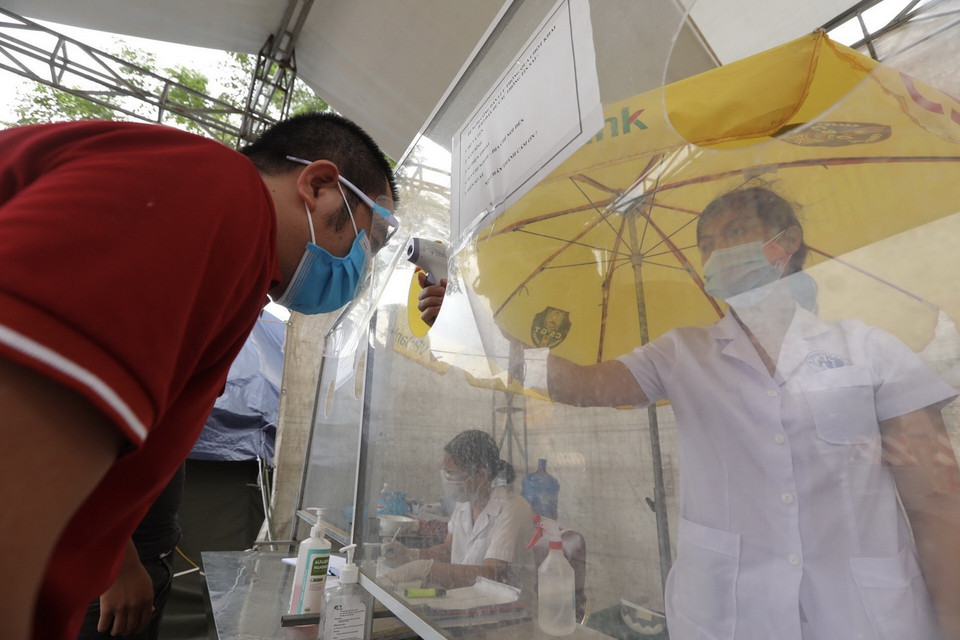  Người tham gia giao thông qua chốt kiểm soát số 18 bắt buộc phải vào chốt kiểm tra thông tin và đo thân nhiệt. (Ảnh: Minh Quyết/TTXVN)